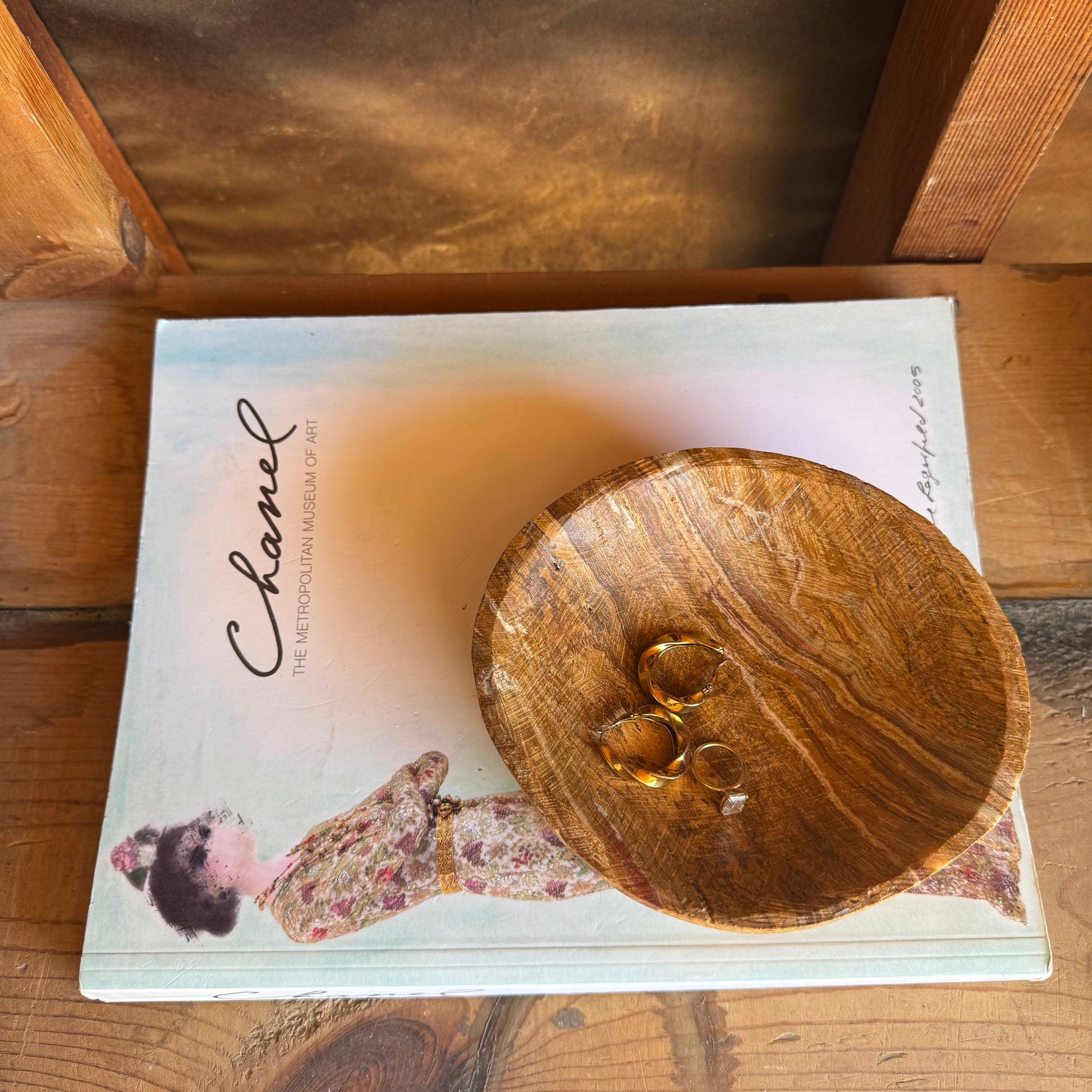 SAÉA onyx catchall bowl styled with gold rings inside, resting on a Chanel book