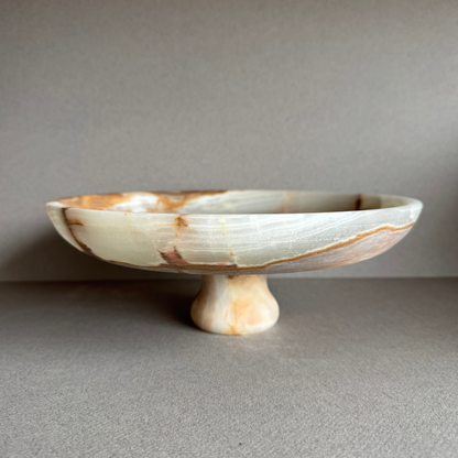 Hand-carved onyx pedestal bowl with honey, cream, and olive veining displayed on a neutral surface
