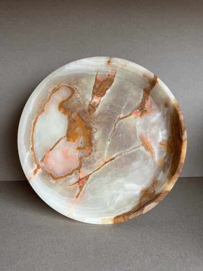 Overhead view of sculptural onyx bowl showcasing natural green and amber veining in a smooth stone surface

