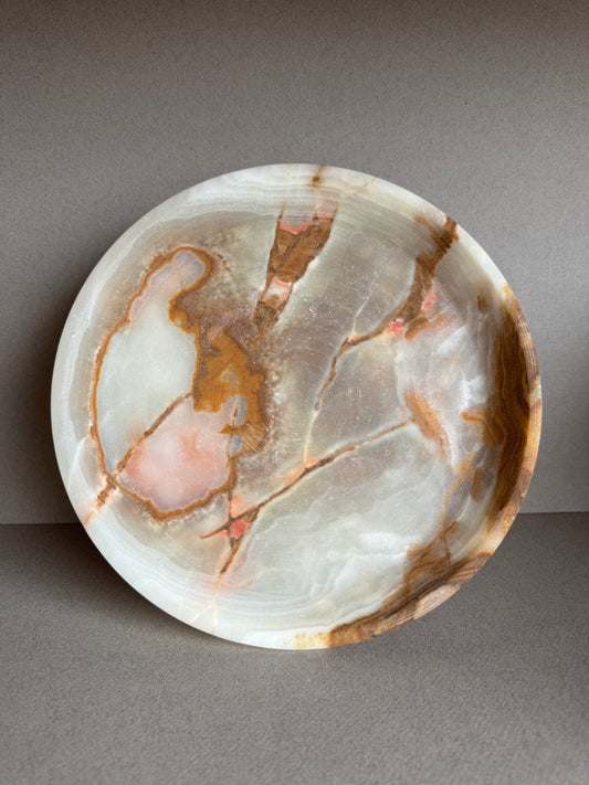 Overhead view of sculptural onyx bowl showcasing natural green and amber veining in a smooth stone surface

