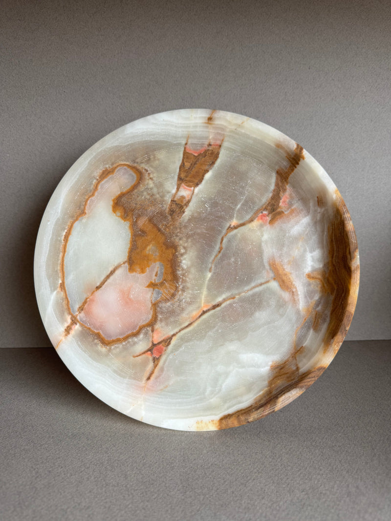 Overhead view of sculptural onyx bowl showcasing natural green and amber veining in a smooth stone surface

