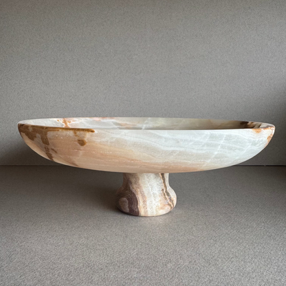 Ash, sage, and ivory onyx pedestal bowl displayed on a minimal surface, showing soft natural veining