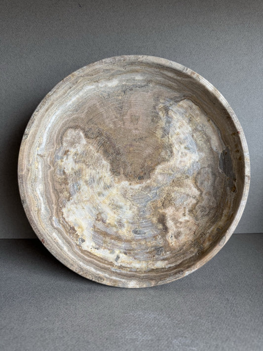 Side view of tall natural stone vase showing smooth matte texture and layered veining.

