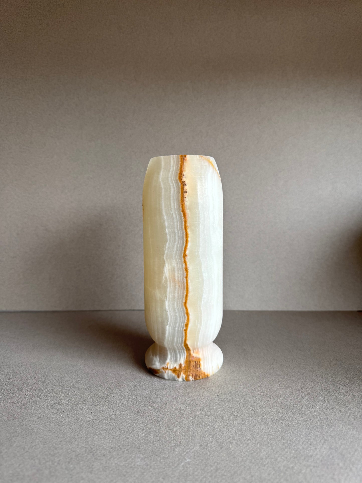 Soft cream-toned side view of vase with light mineral patches and warm base.

