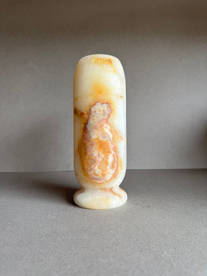 Rear floral-styled view of vase with soft golden-pink stone gradient and pedestal base.


