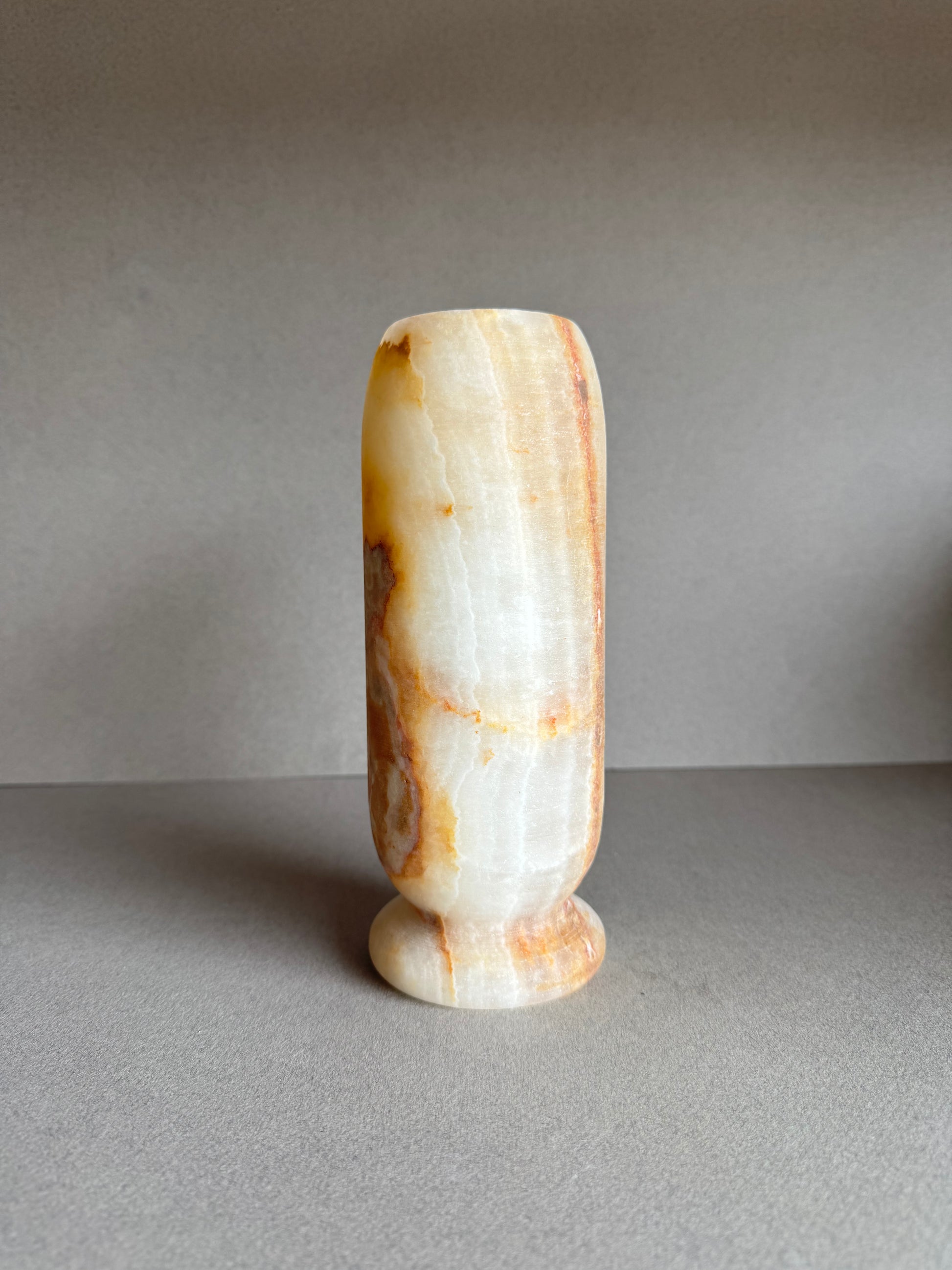 Onyx vase in soft honey and peach tones with marbled amber mineral bloom on front.

