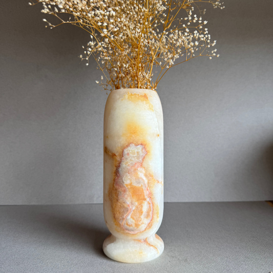Vase styled with dried florals, front bloom detail visible in warm light.

