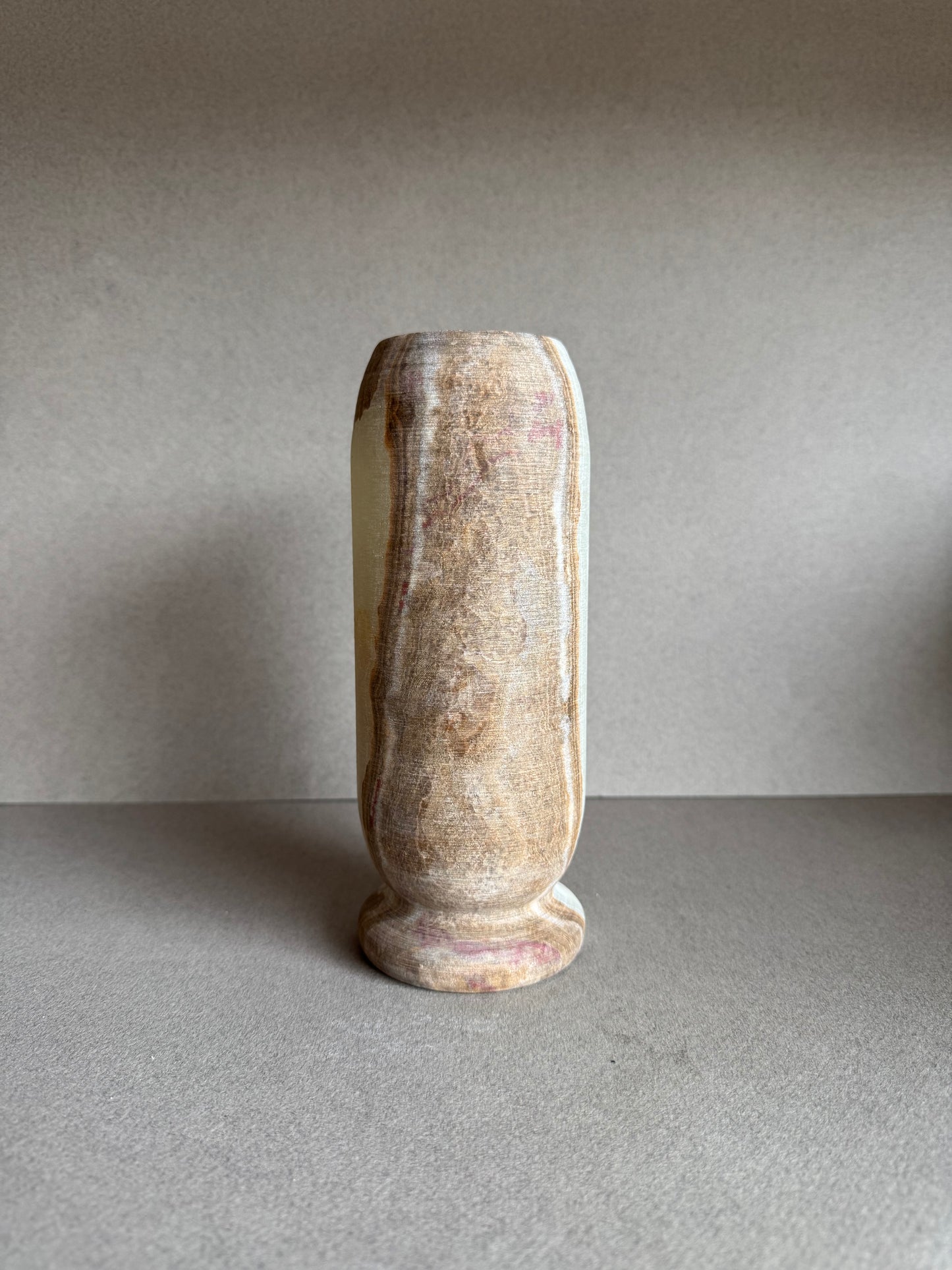 Rear view of the vase with smooth stone texture and blush-toned mineral markings.

