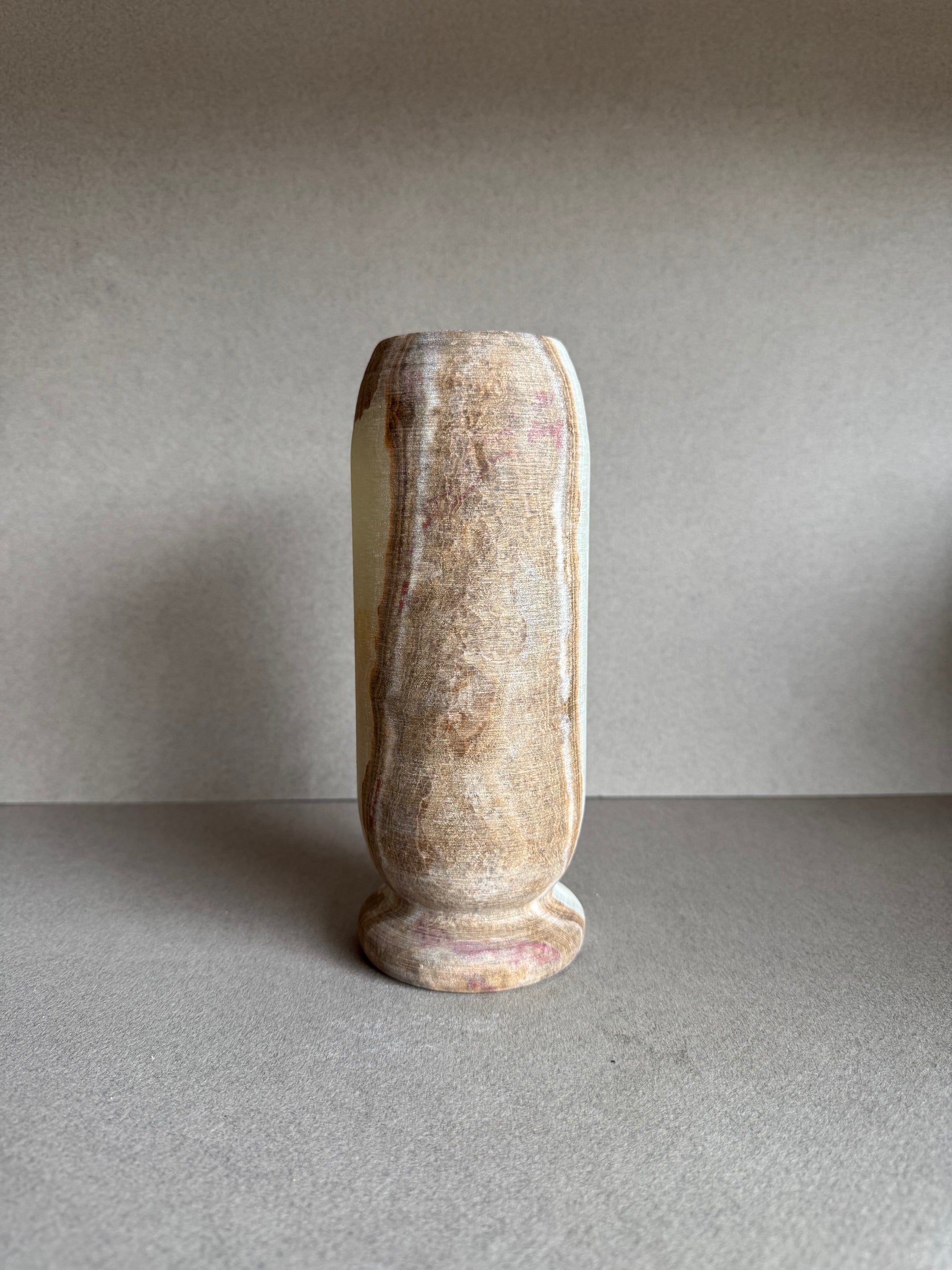 Rear view of the vase with smooth stone texture and blush-toned mineral markings.


