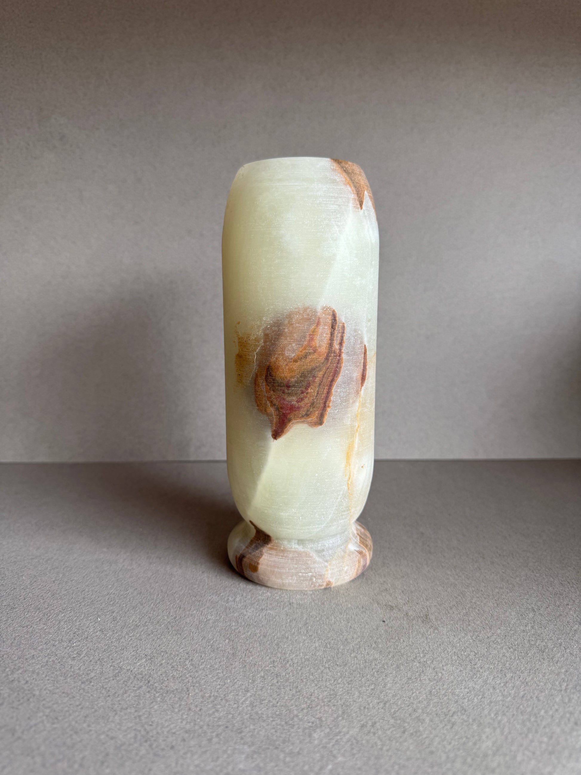 Rear view of the vase with smooth stone texture and blush-toned mineral markings.

