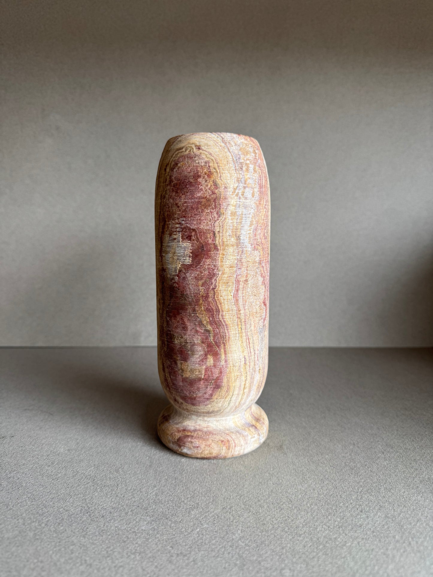 Front angle of tall vase showing clay and blush banding with natural onyx character.

