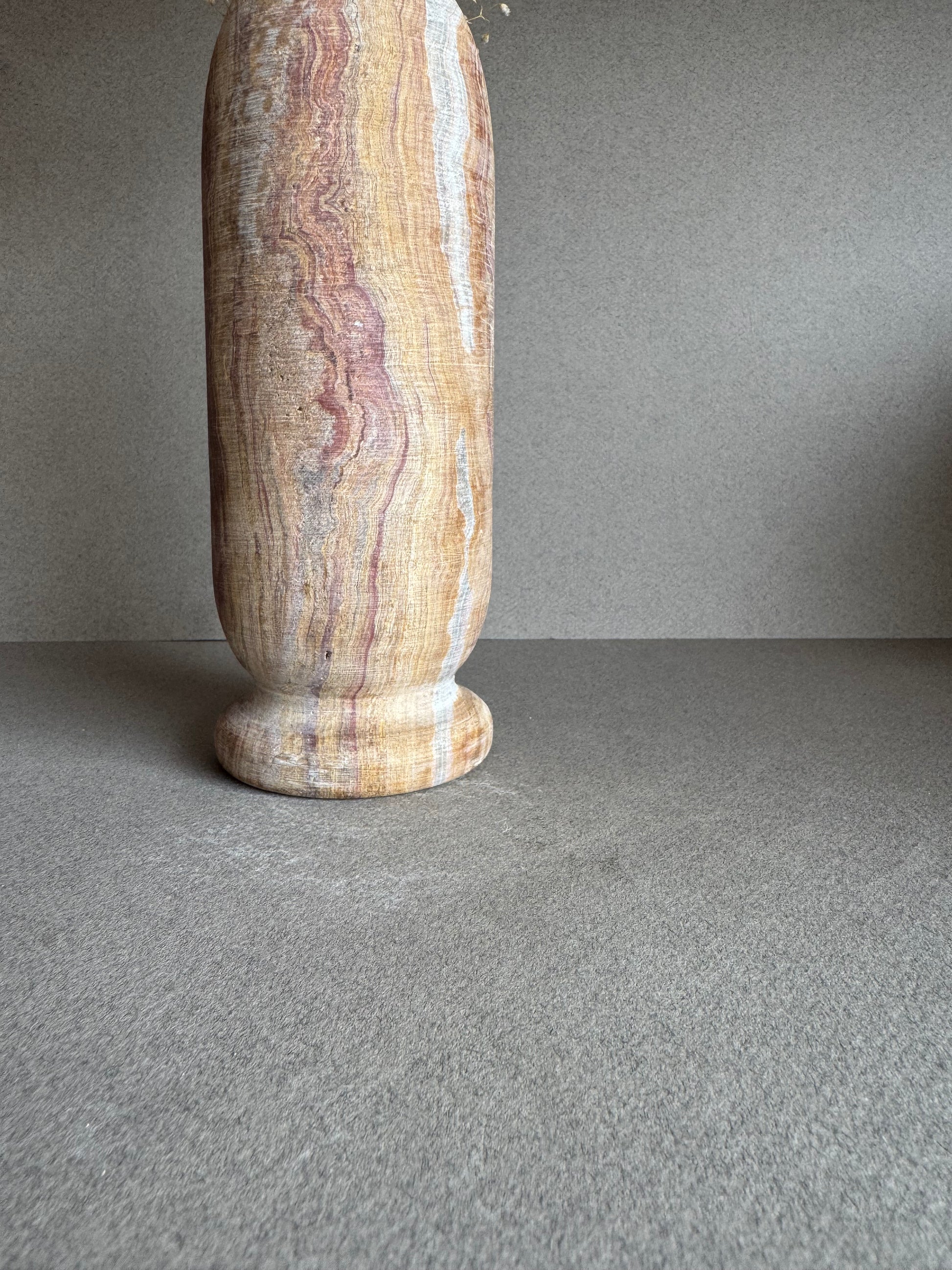 Side view showing warm striations of tan, pink, and white on natural stone.

