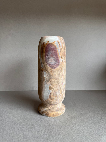 Tall onyx vase with dramatic rose-toned mineral bloom, hand-carved with a pedestal base and natural matte finish.

