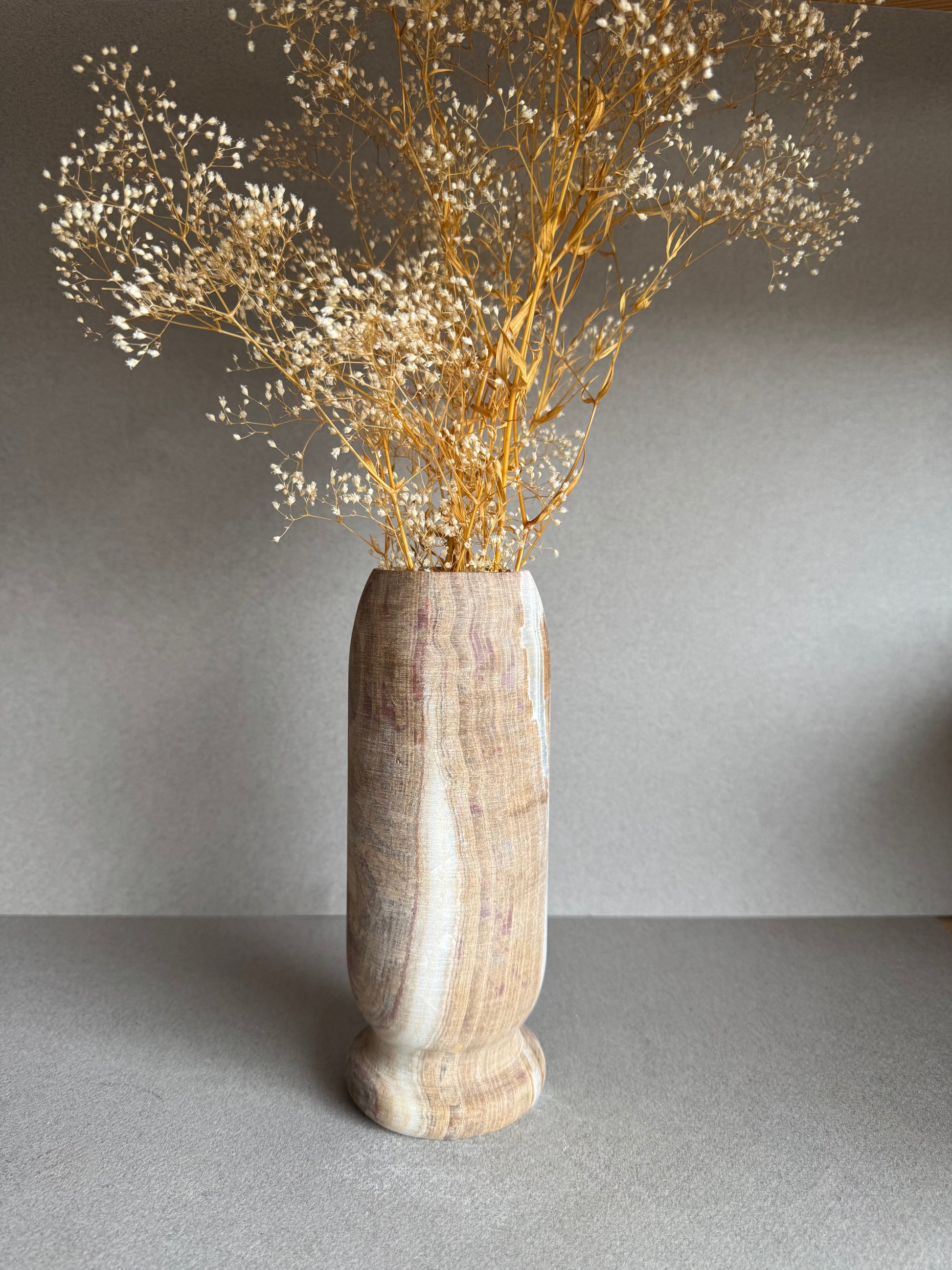 Vase styled with dried florals, showcasing sculptural form and muted rosewood tones.

