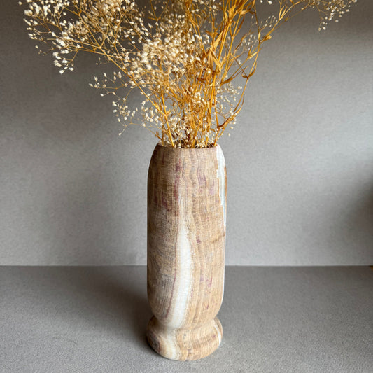 Vase styled with dried florals, showcasing sculptural form and muted rosewood tones.

