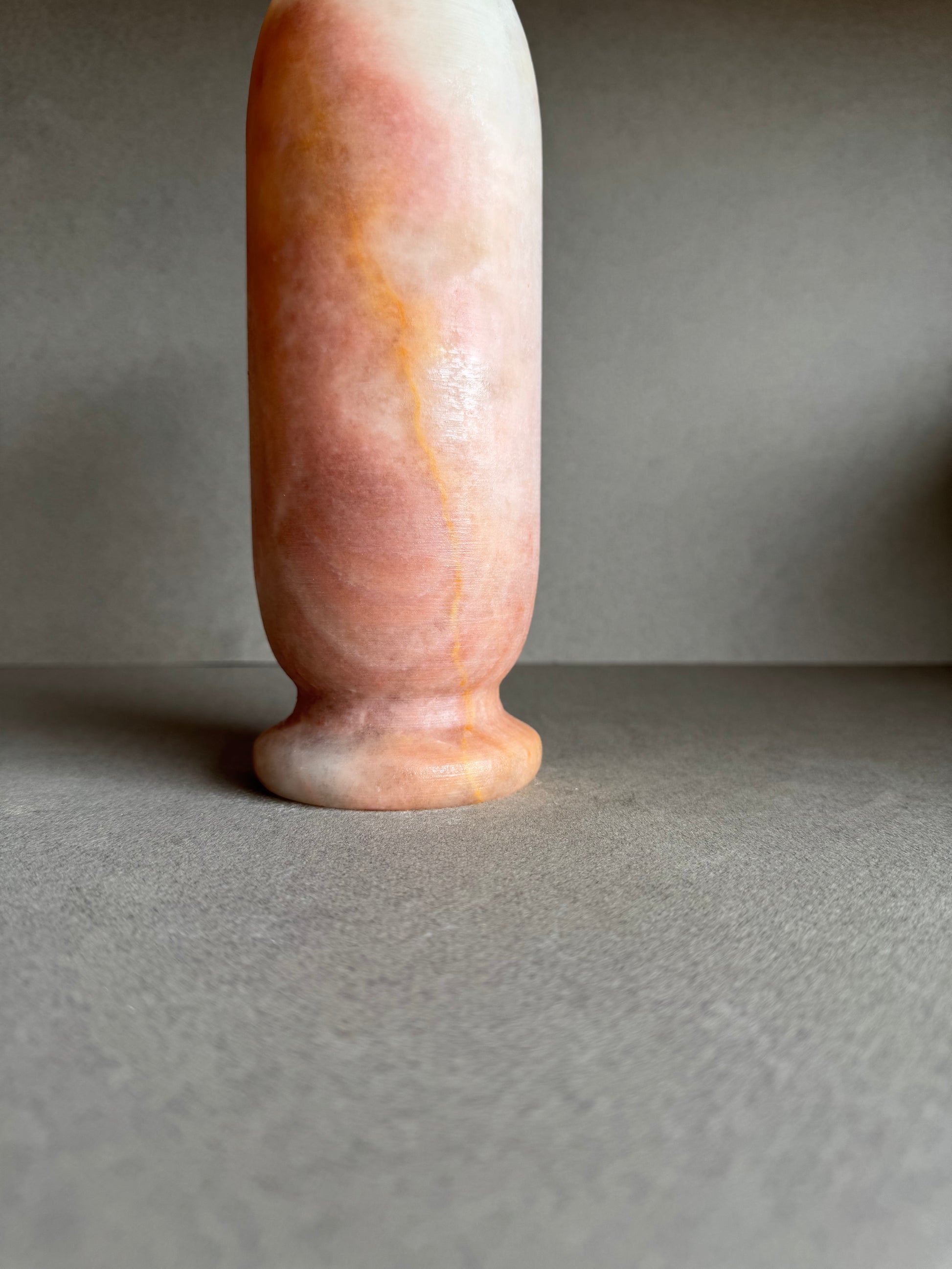 Close-up of base showing soft terracotta curves and cloudy mineral banding.

