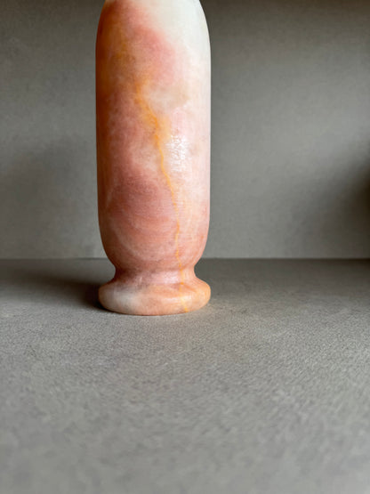 Close-up of base showing soft terracotta curves and cloudy mineral banding.

