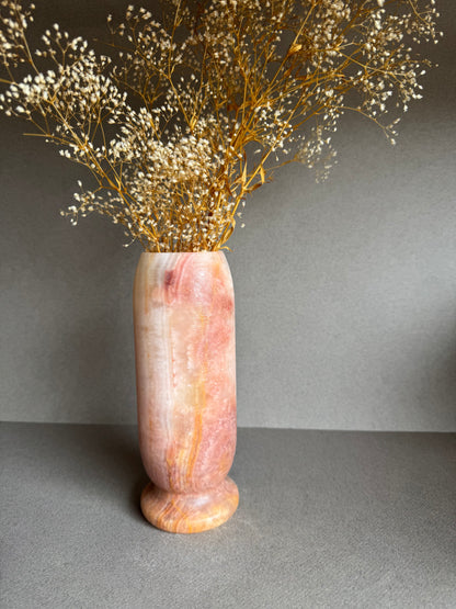 Vase styled with dried baby’s breath, highlighting warm pink and clay-like tones.

