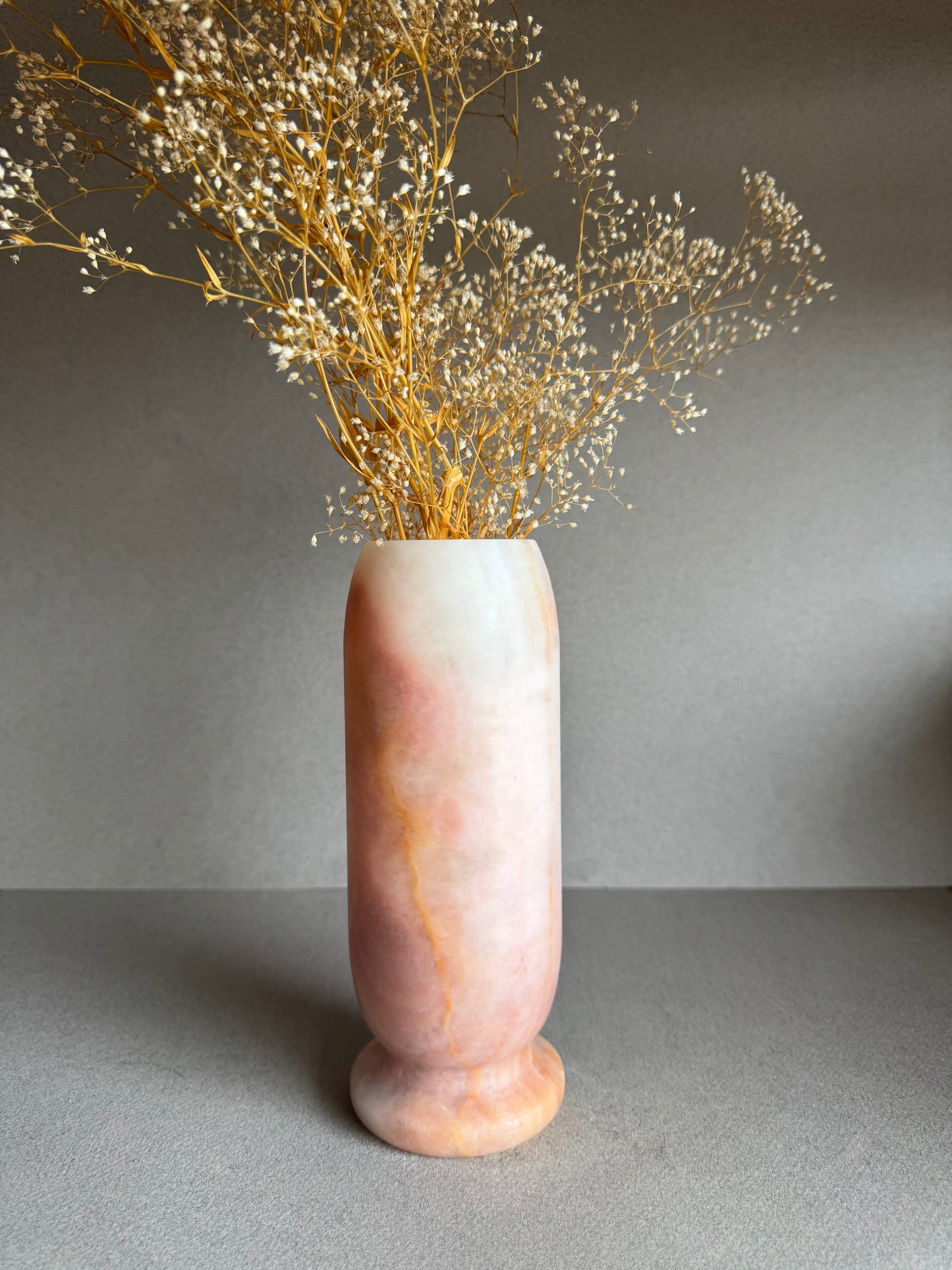 Vase styled with dried baby’s breath, highlighting warm pink and clay-like tones.

