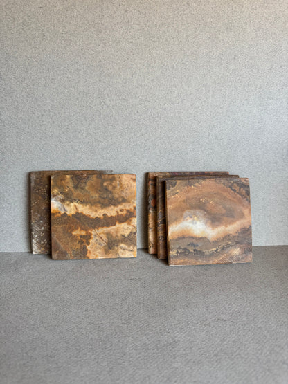 Flat lay of 5 square onyx coasters showing unique amber, honey, and cream veining

