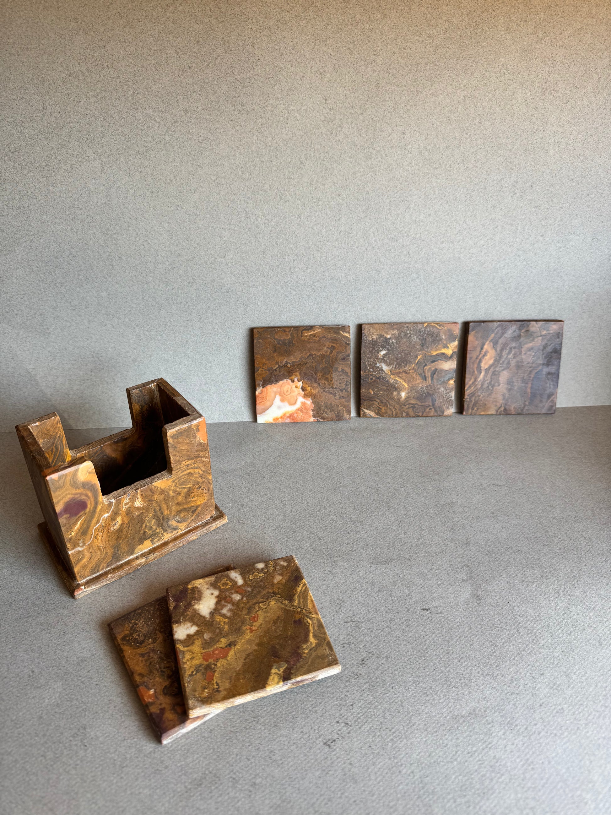 Onyx coaster set in rust, ochre, and maroon tones with holder and coasters displayed in front