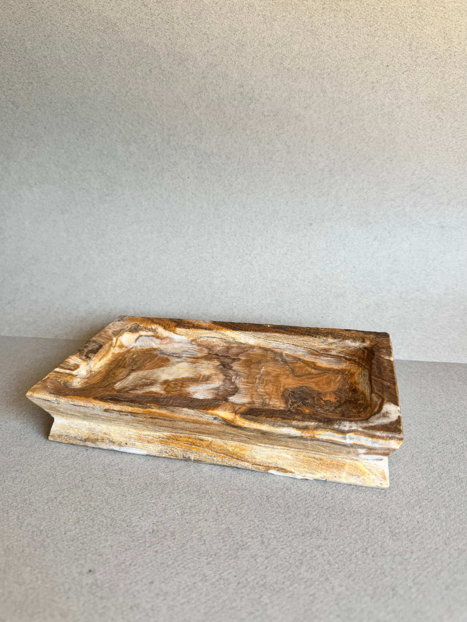 Side angle of rectangular natural stone tray with marbled amber veining

