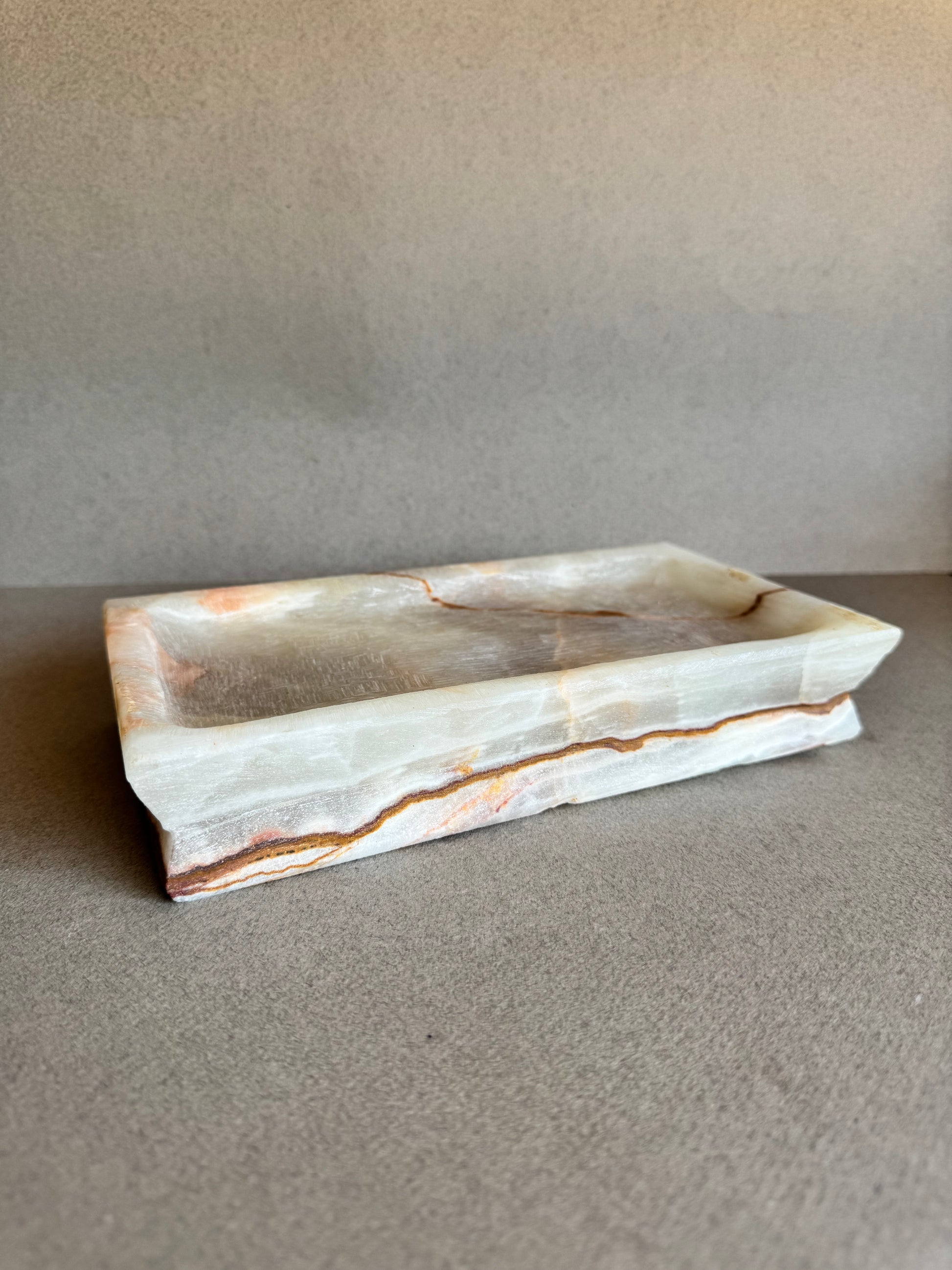 Rectangular ivory onyx tray with rust veining on neutral background