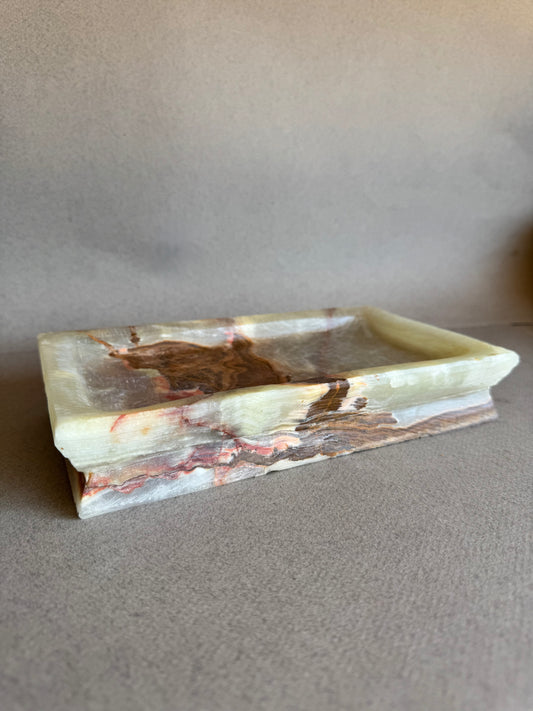 Hand-carved onyx catchall tray in cream, rust, and deep red with layered marbling and stepped edges

