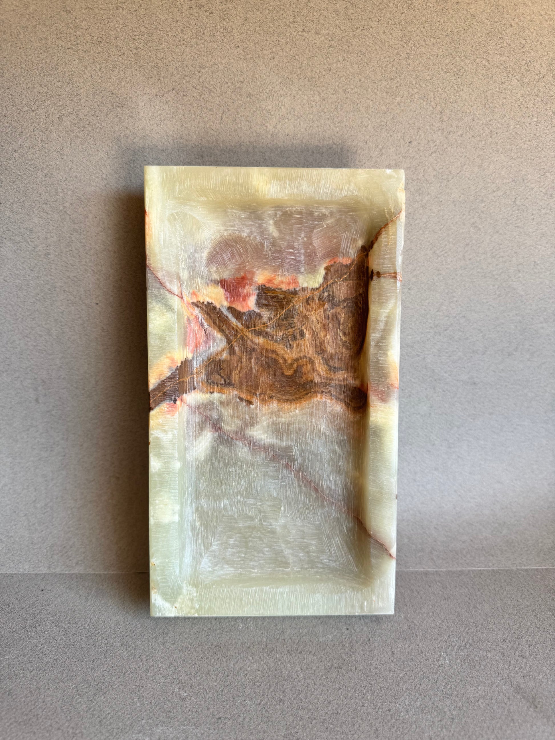 Top-down view of catchall tray showcasing a dramatic onyx pattern in rust and red


