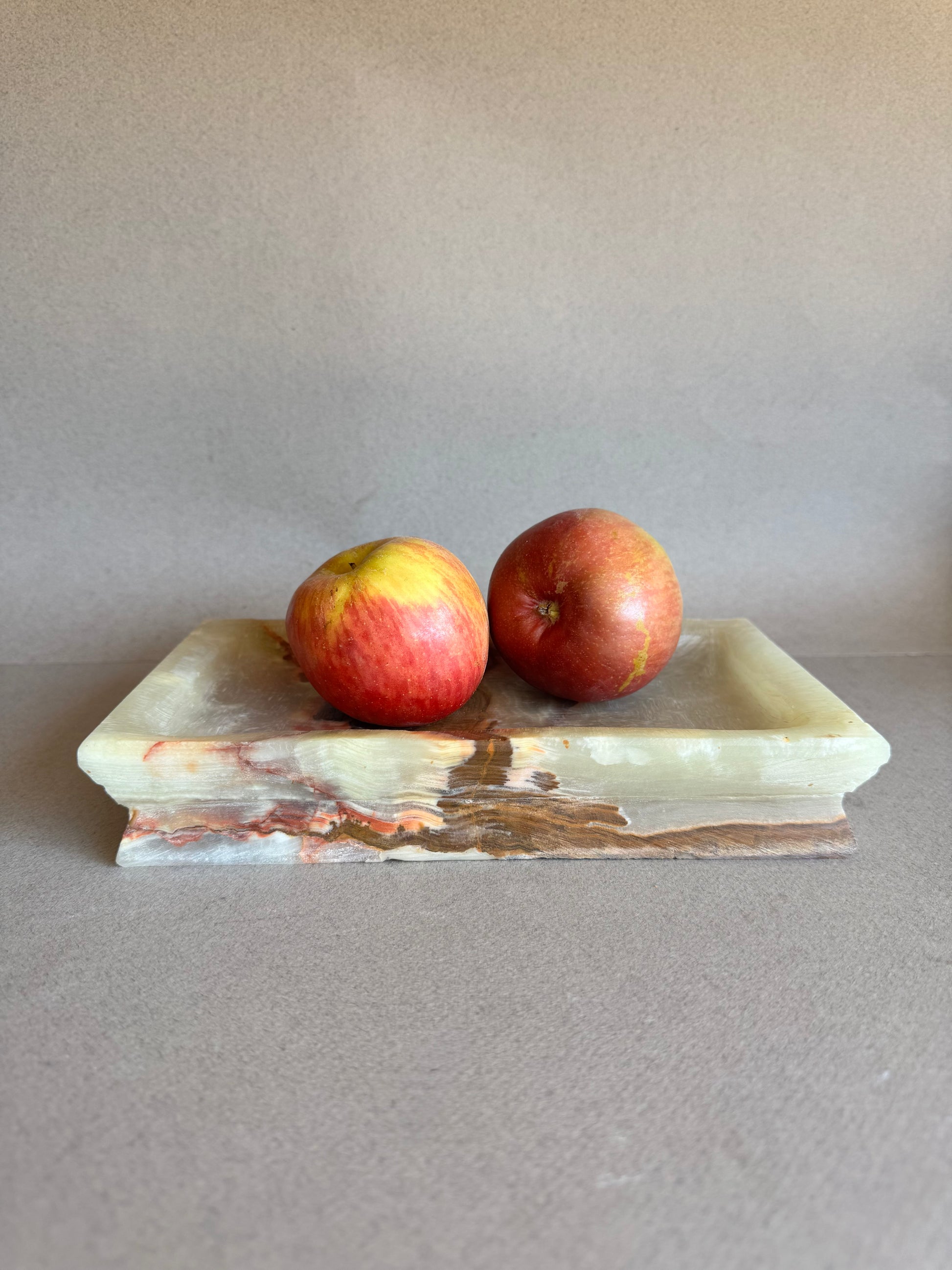 Onyx tray styled as a fruit dish with apples, highlighting its warm earthy veining

