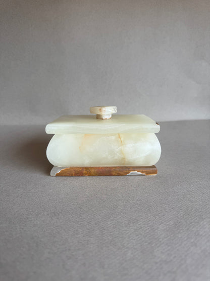Hand-carved stone box with sculptural pull lid, resting on neutral surface

