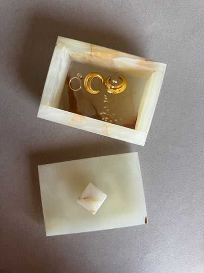 Open onyx box with cream and blush interior, styled with small items inside

