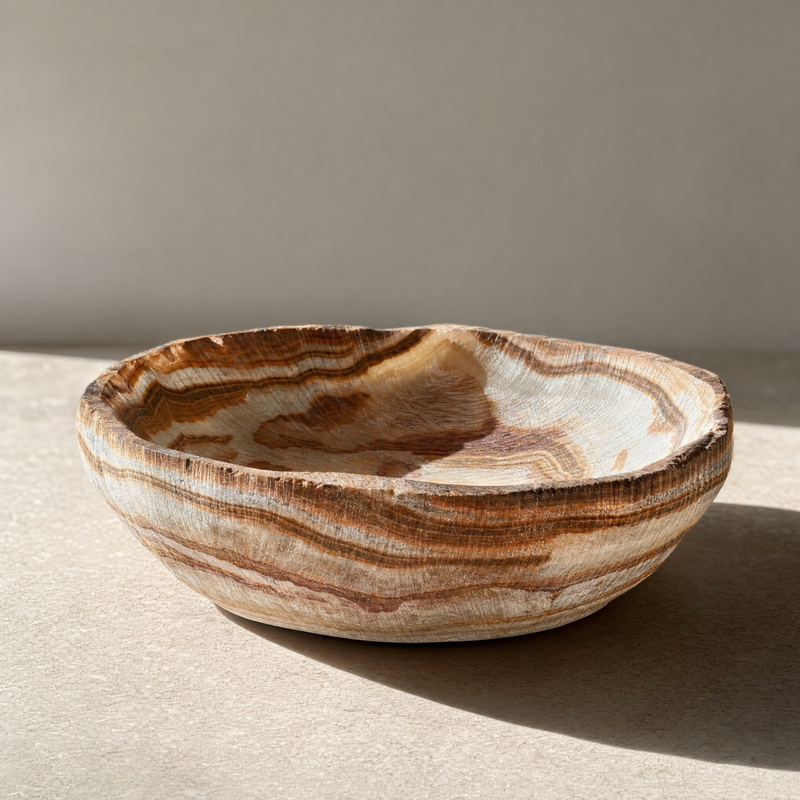Side angle of raw onyx catchall bowl highlighting layered brown banding and rough-cut rim.
