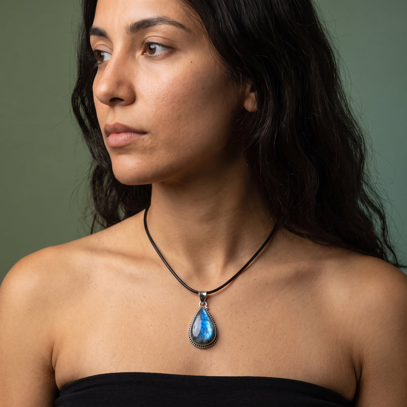 Dark moonstone teardrop pendant on a short black leather cord, blue flash in a beaded sterling silver bezel