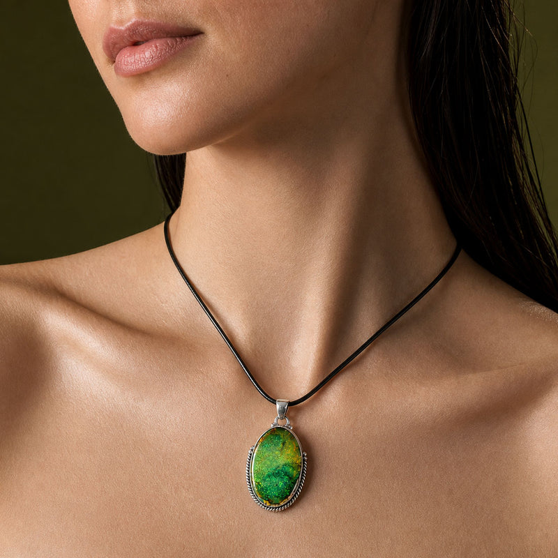 Emerald and lime green Australian opal oval pendant in a rope-twist sterling silver bezel, worn on a short black leather cord at the collarbone.