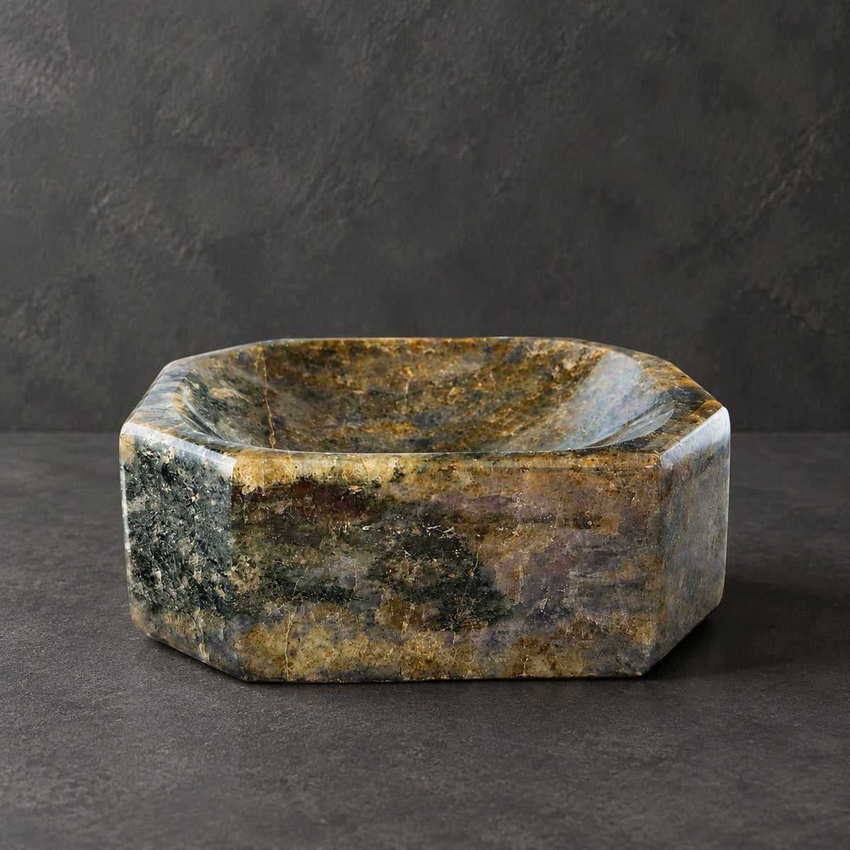 Moss green and bronze labradorite octagon catchall bowl, side view of its eight hand-cut faces against a dark gray ground