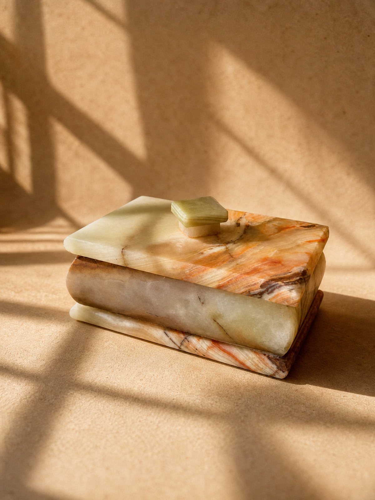 Sage-green onyx lidded box with square knob, cream and amber body, in warm light