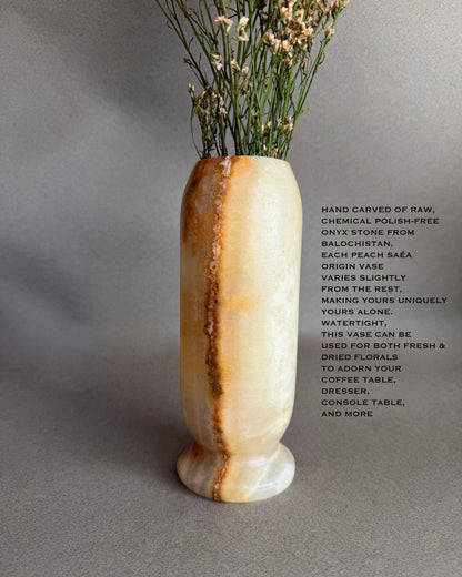 Peach Honey Onyx natural stone vase with dried flowers on a gray background