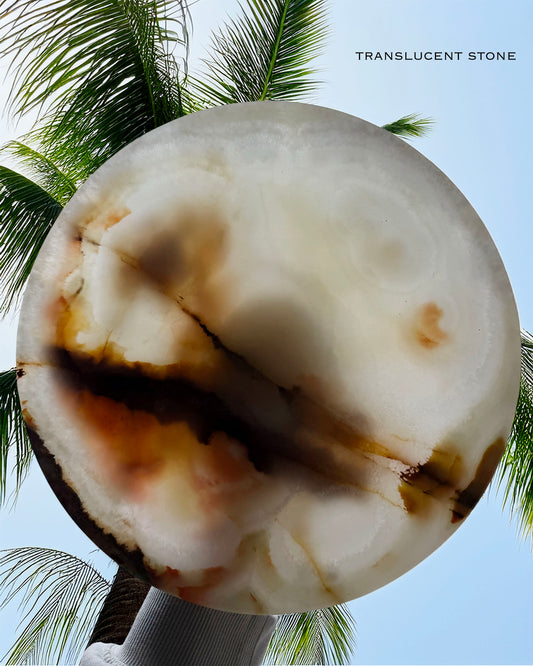 Translucent stone bowl with brown markings against a palm tree and blue sky background