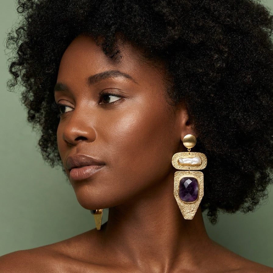 Model wearing an amethyst and freshwater pearl drop earring in hammered 22k gold plate