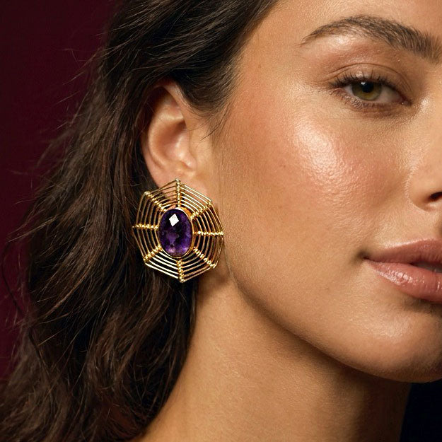 Close-up of a faceted amethyst wire web stud in 22k gold plate, worn on the ear