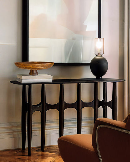 Black console table with decorative items against a wall with abstract art