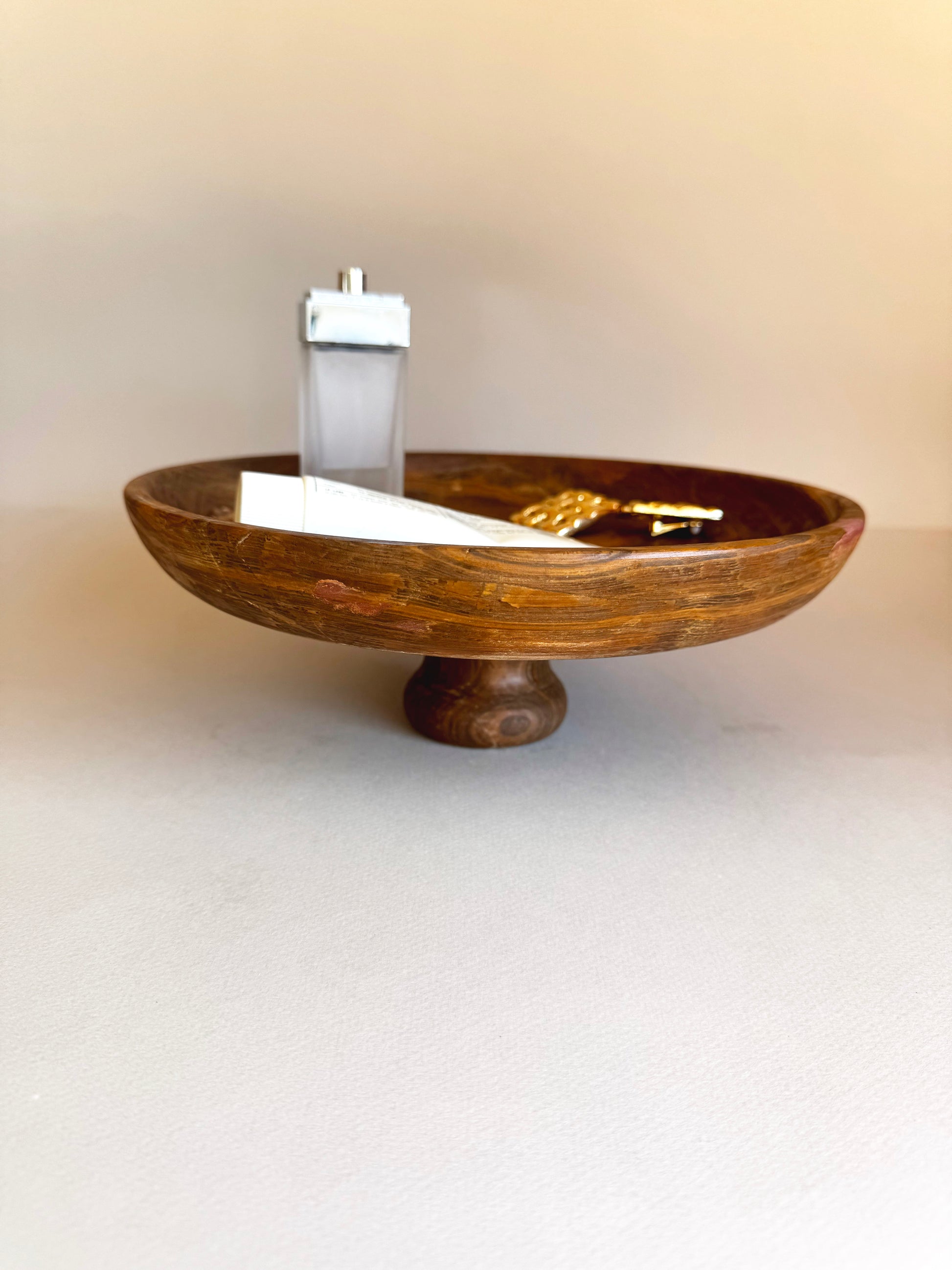 Wooden bowl with a white candle on a beige background