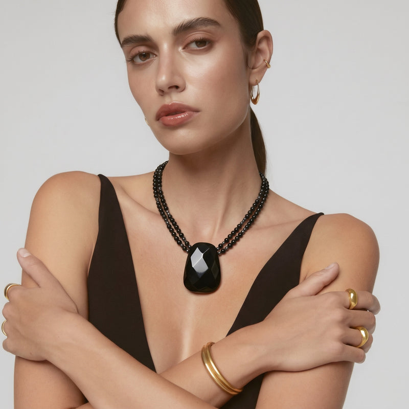 Model wearing the faceted black onyx pendant necklace on a double strand of black beads