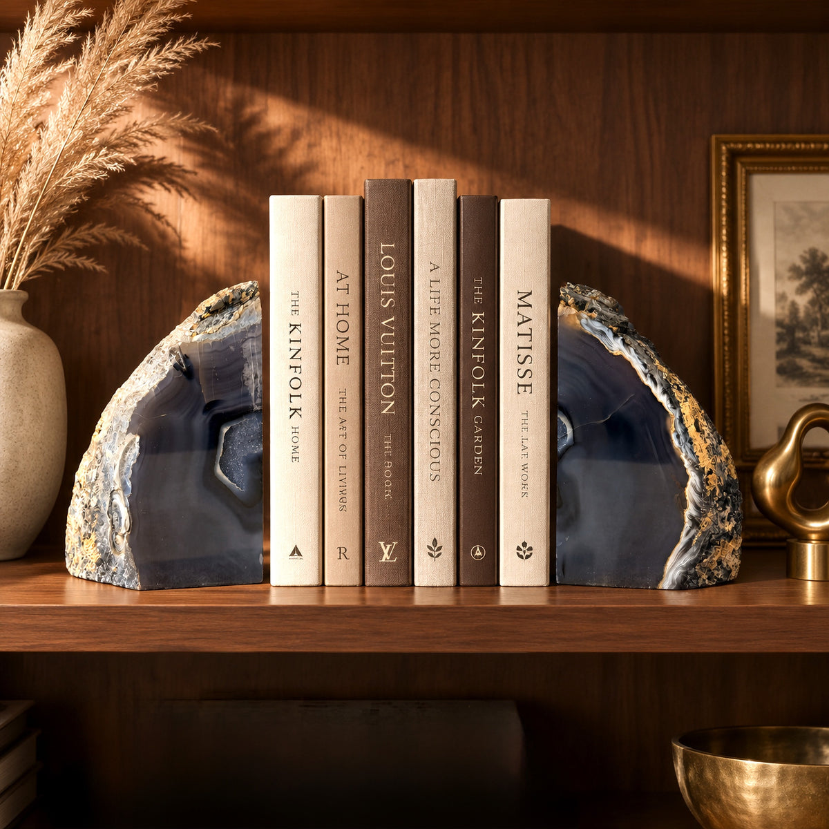 Pair of slate-blue agate geode bookends holding a row of hardcover books on a wooden bookshelf