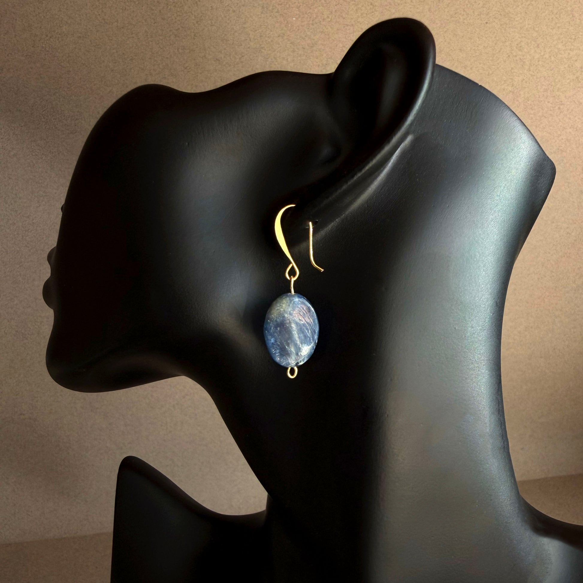 Handmade blue kyanite drop earring on matte black display, featuring natural oval blue gemstone with gold filled hook
