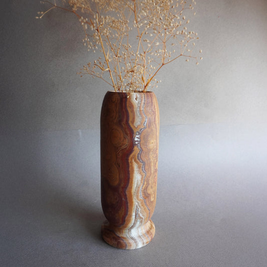Hand-carved tall onyx vase in warm brown, ivory, and golden rust tones, sculptural stone vessel for flowers or modern home decor
