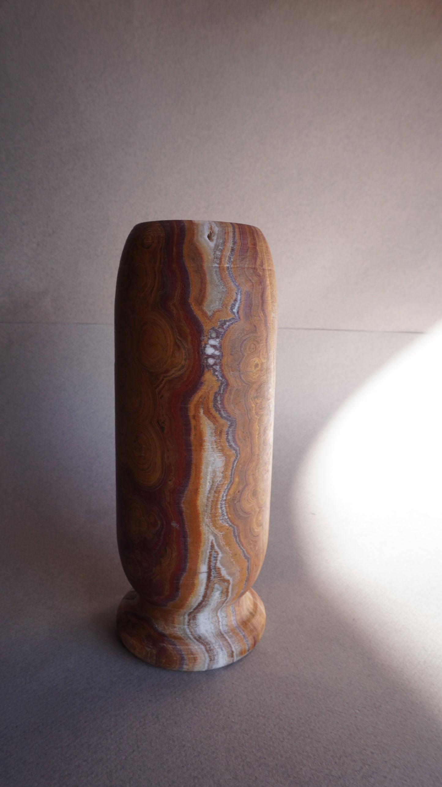 Close-up of brown onyx vase base showing natural stone veining and handcrafted texture
