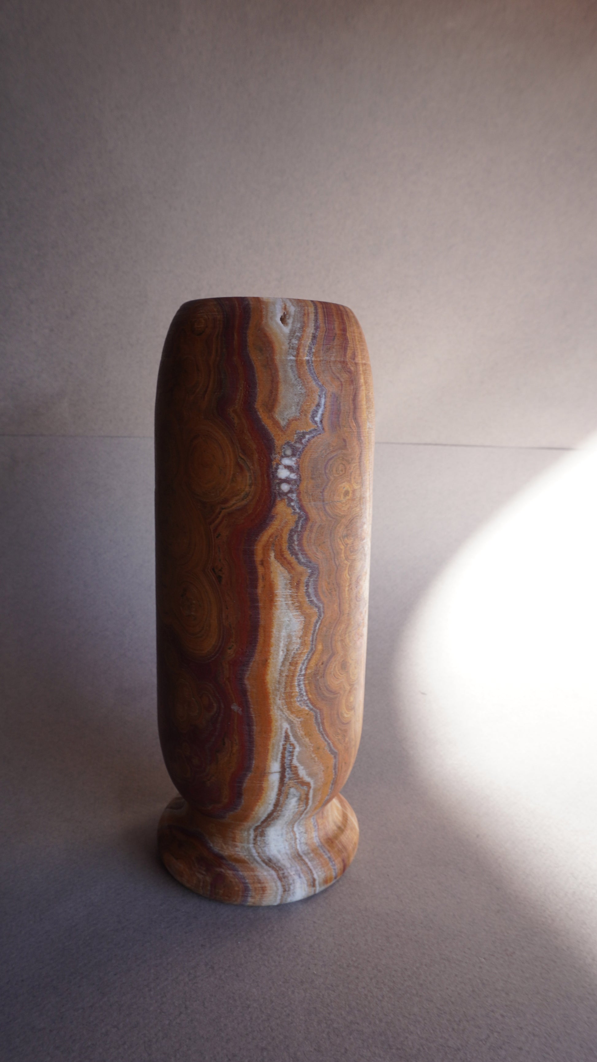 Close-up of brown onyx vase base showing natural stone veining and handcrafted texture
