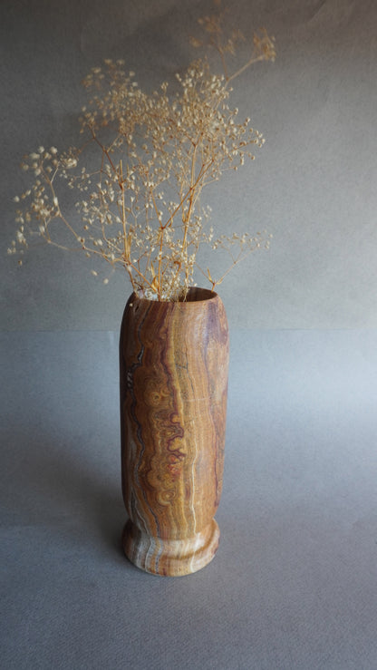 stone vase with dried flowers on a gray background